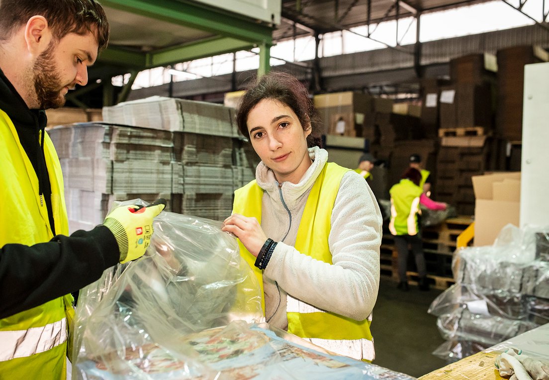 Mitarbeiter sortieren Materialien in einer Lagerhalle.