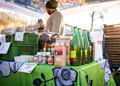 Verkaufsstand mit verschiednen Produkten, im Hintergrund 2 Verkäufer