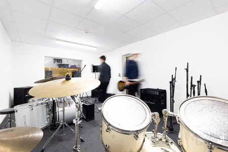 ein Jugendlicher im Tonstudio mit vielen Musikinstrumente zur Verfügung