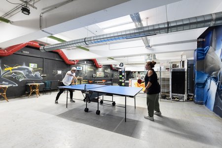 Jugendliche spielen Tischtennis in einem mit Graffiti gestalteten Raum