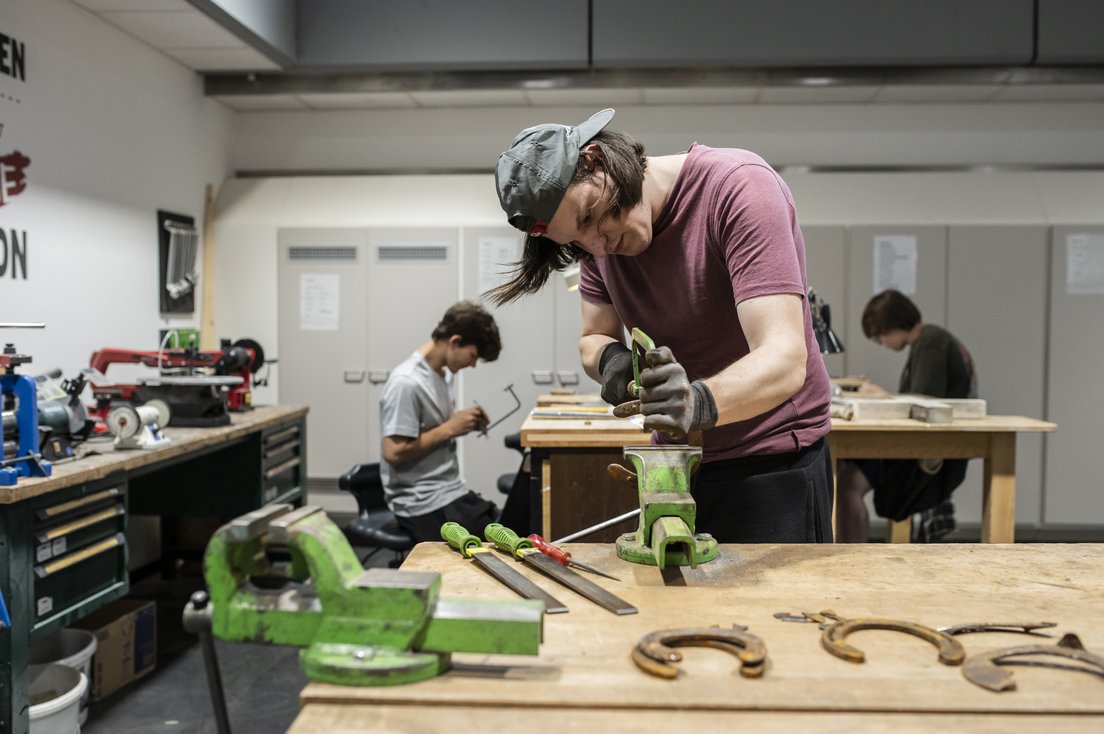 drei Jugendliche arbeiten in einer Metallwerkstatt