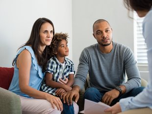 Eine Familie bestehend aus Vater, Mutter, Kind wird gerade beraten