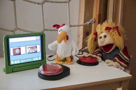Kuscheltiere und ein iPad mit Sehübungen auf einem kleinen Tisch