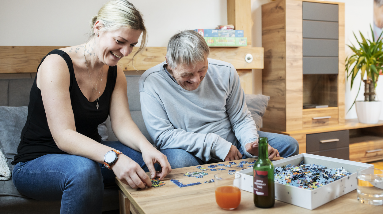 Ein Kunde und seine Betreuerin bauen ein Puzzle